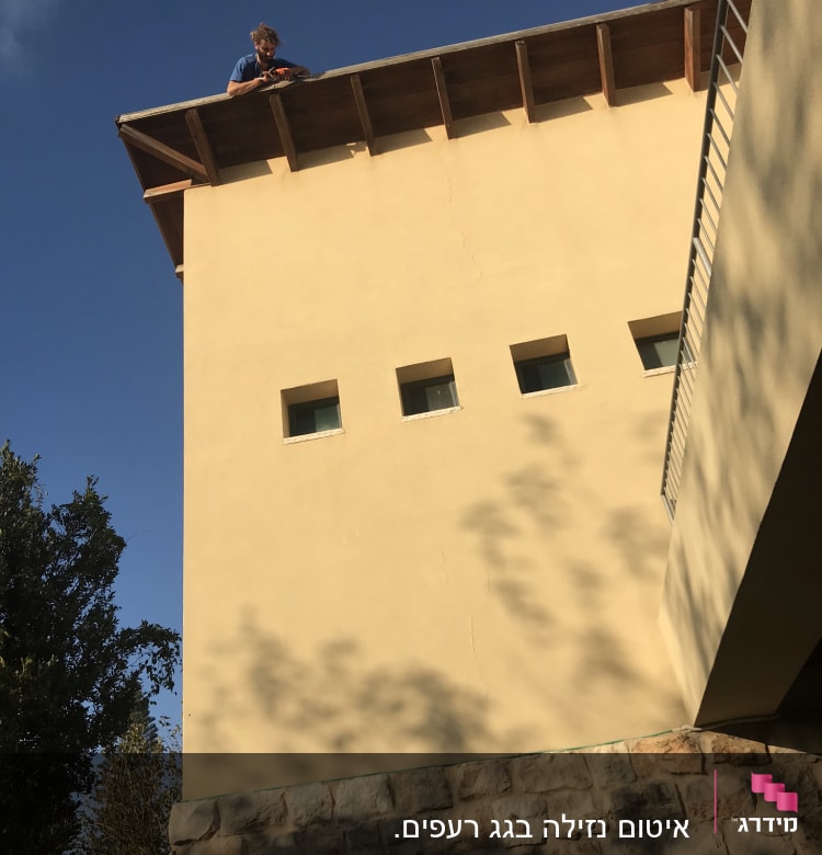 אדם עומד על גג עם כלי עבודה ביד